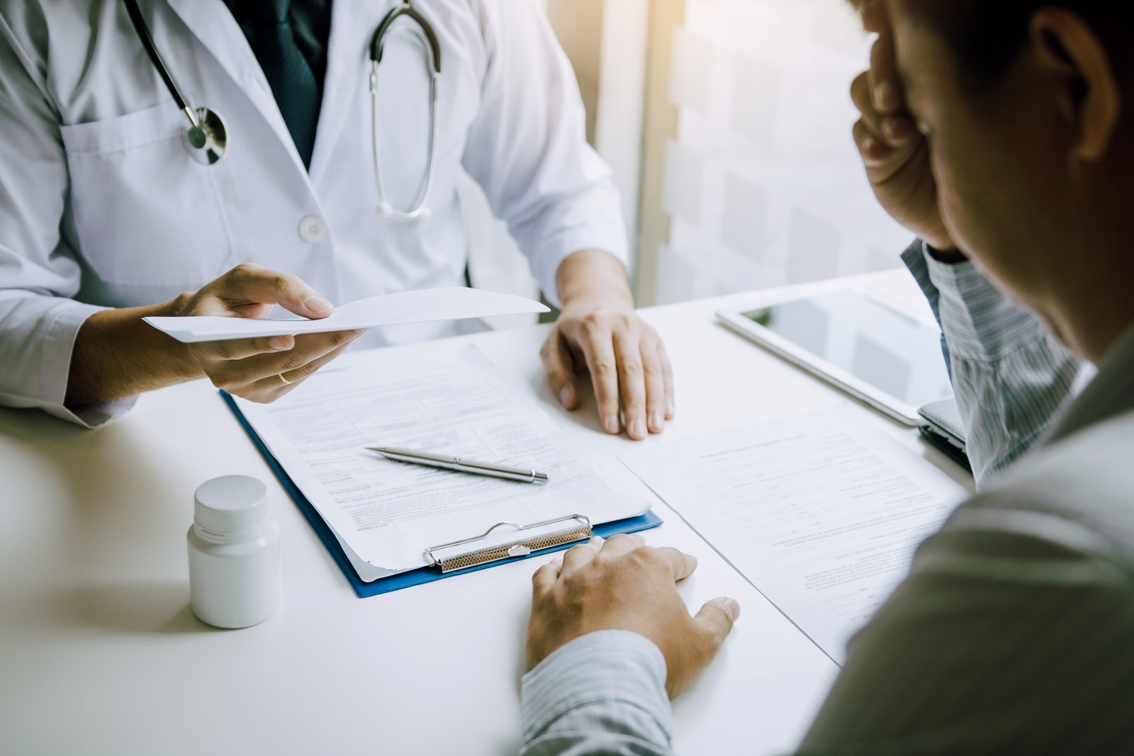 A physician handing visit paperwork to a patient